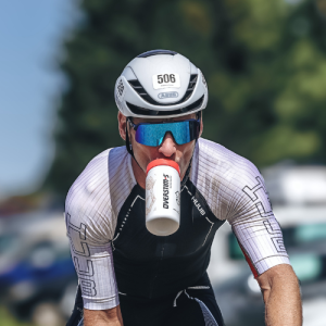 Triathlete de l'Alpe d'Huez avec un bidon Overstims dans la bouche.